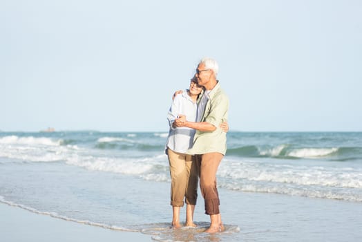 Happy Asian senior man and woman couple smile dancing resting relax on the beach honeymoon family sunny day, Romantic elderly enjoy travel summer vacation, plan life insurance at retirement couple