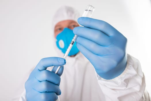 COVID-19 coronavirus vaccine. Vaccination concept. Doctor's hand in blue gloves hold medicine vaccine vial bottle and syringe.