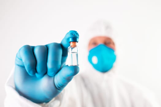 COVID-19 coronavirus vaccine. Vaccination concept. Doctor's hand in blue gloves hold medicine vaccine vial bottle and syringe.