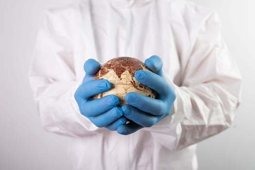 World epidemic danger concept. Male doctor man in medical face mask and gloves protecting planet Earth.