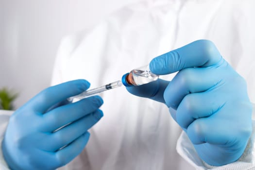 COVID-19 coronavirus vaccine. Vaccination concept. Doctor's hand in blue gloves hold medicine vaccine vial bottle and syringe.