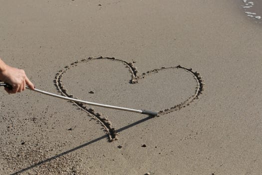 Drawing a heart on a sandy beach