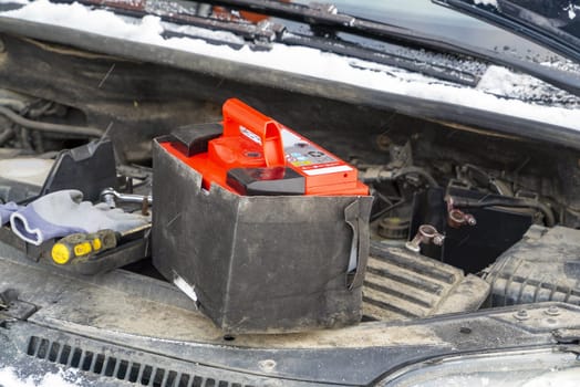 A new battery in the engine compartment of the car in winter