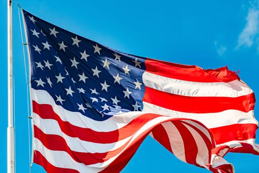 US american flag and blue cloudy sky with clouds in background