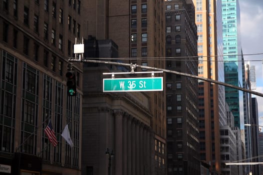 Green big West 35th Street sign hanging on a arch pole in the streets of midtown Manhattan in New York City