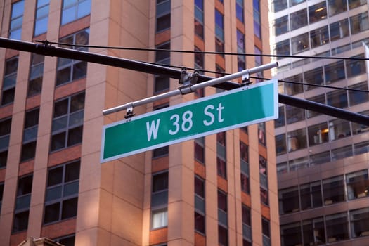 Green big West 38th Street sign hanging on a arch pole in the streets of midtown Manhattan in New York City