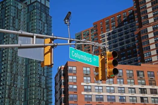 Green big Columbus Drive sign hanging on a arch pole between traffic lights in the streets of downtown Jersey City
