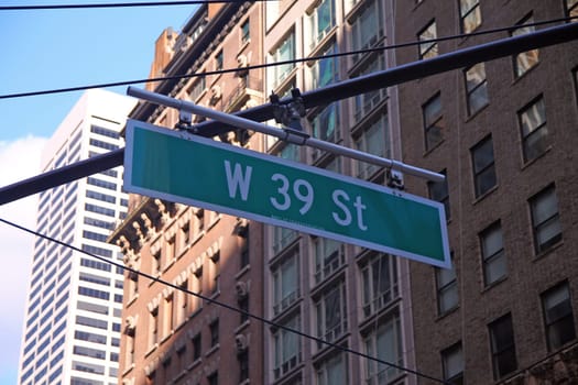 Green big West 39th Street sign hanging on a arch pole in the streets of midtown Manhattan in New York City