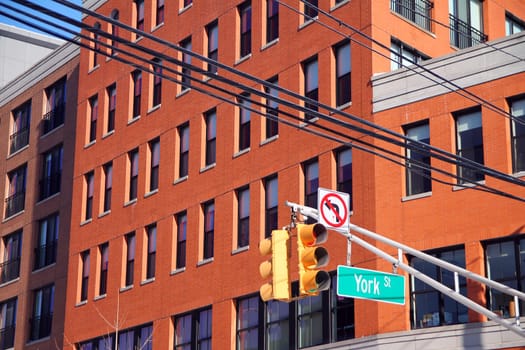 Green big York Street sign hanging on a arch pole between traffic lights in the streets of downtown Jersey City