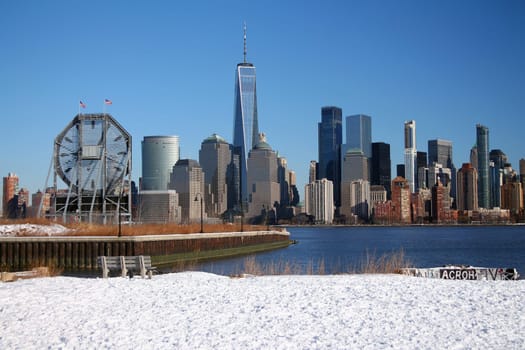 The bench and the big clock looking at downtown Manhattan with the snow on the ground from Liberty State Park in Jersey City