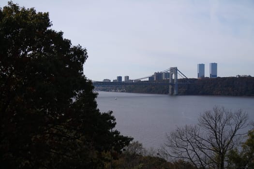 Part of the Washington bridge behind the trees on the Hudson river in New York City
