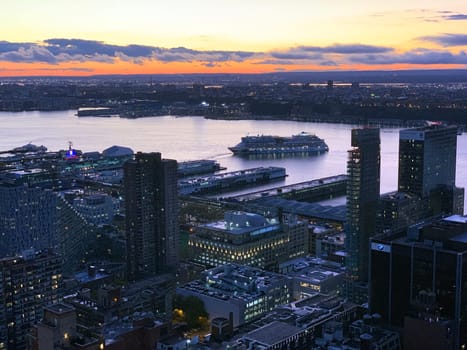 A dramatic shot of a cruise leaving the harbour during a violet sunset on the Hudson River in Manhattan in New York City