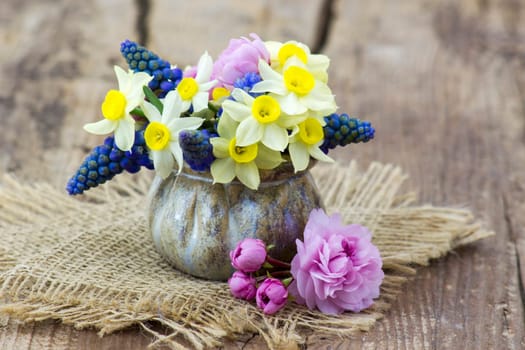 spring flowers bouquet in a vase on wooden background