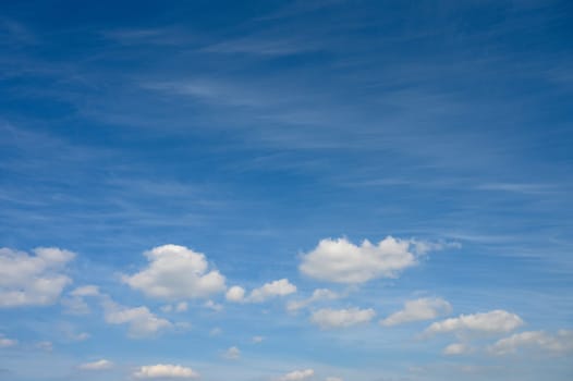 Fluffy white clouds float gracefully across a brilliant blue sky, creating a tranquil midday atmosphere.