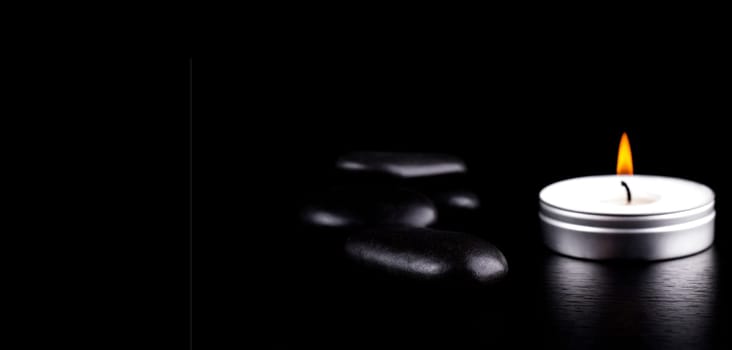 The Close-up of black stones and candle on black background. Lifestyle concept