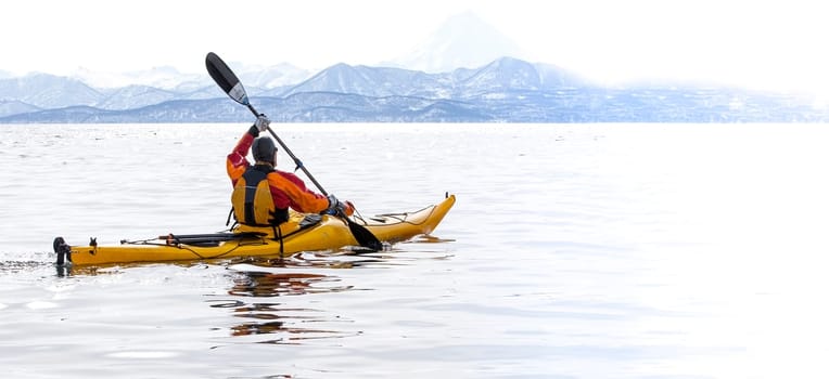 The kayaker on a boat in the calm sea on Kamchatka Peninsula