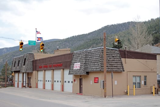 Idaho Springs, CO, USA - April 19, 2014: Front and side of modern fire department building with Colorado and American flags. Semi profile view of an Idaho Springs fire department with evergreen tree mountains in the background.