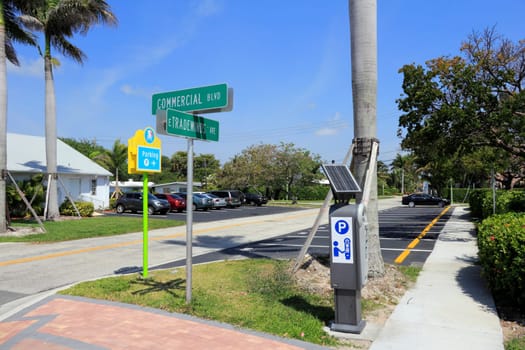 LAUDERDALE-BY-THE-SEA, FL, USA - APRIL 7, 2014: Solar powered digital public parking meter and parking spaces north of intersection of Commercial Blvd and E Tradewinds Ave.  About fourteen public parking spaces in the lot at the corner of E Tradewinds Ave and Commercial Blvd. on a sunny day.