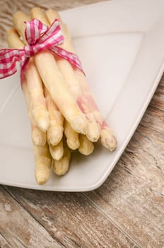White asparagus with a decorative bow on a white plate