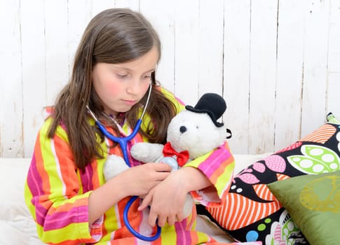 a sick little girl playing with her teddy in her bed