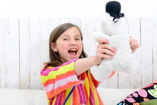 a little girl playing with her teddy in her bed