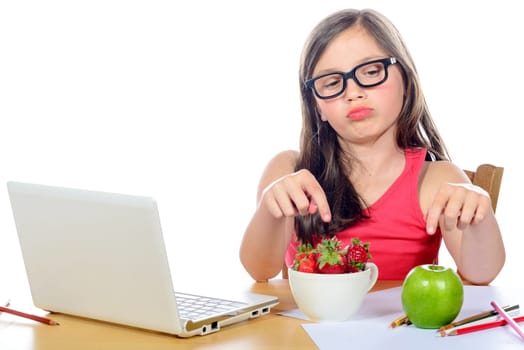 a little girl at her desk looking at his snack on white