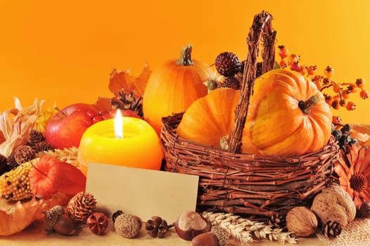 Thanksgiving – various pumpkins,nuts,corn and apple in the rattan basket with candlelight and text space