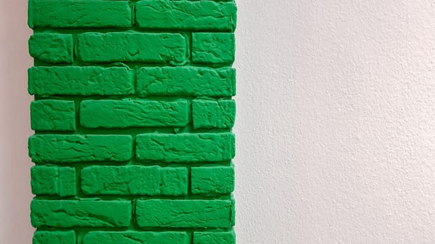 Modern new flat pink wall with a decorative brick column painted green. Abstract modern trendy texture background. Copy space empty space for your text and advertisement