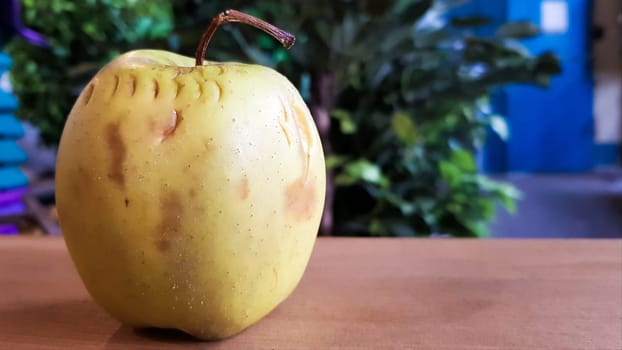 green rotten apple on a wood background. Green apple on a old wooden background, top view. Organic juicy bio apple ugly, with defects edible lies on a wooden table. No ugly food.