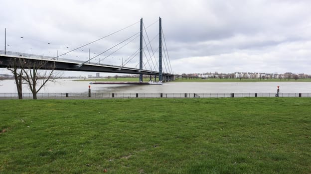 Dusseldorf, Germany - February 20, 2020: view of the Rhine river, promenade and bridge. View over a walk on the banks of the Rhine river in Dusseldorf on a clear spring day, North Rhine Westphalia