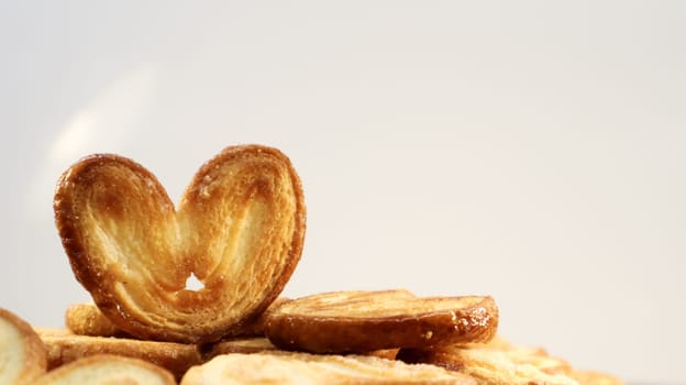 Fresh puff pastry palm cookies in the shape of a heart. Classic French pastries. Pig ear, elephant ear cookies, French hearts