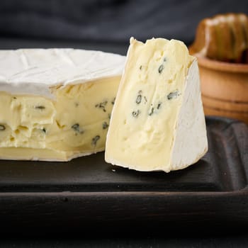 bergader blue cheese on a brown wooden board, delicious snack