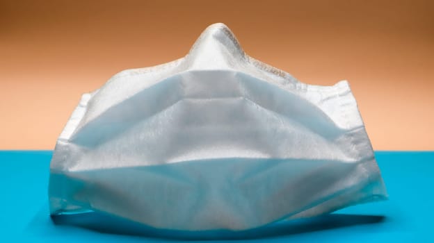 One 3-layer disposable surgical face mask with rubber pads to cover the mouth and nose. The concept of protection from bacteria, healthcare and medicine. COVID-19. Dangerous virus.