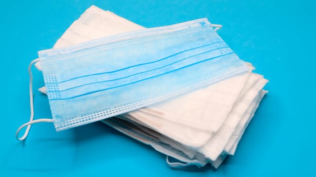 Coronavirus protection. Antiviral protective medical face masks with ear loops. Surgical mask background. Respiratory syndrome, coronavirus disease COVID-19. Many folded medical masks