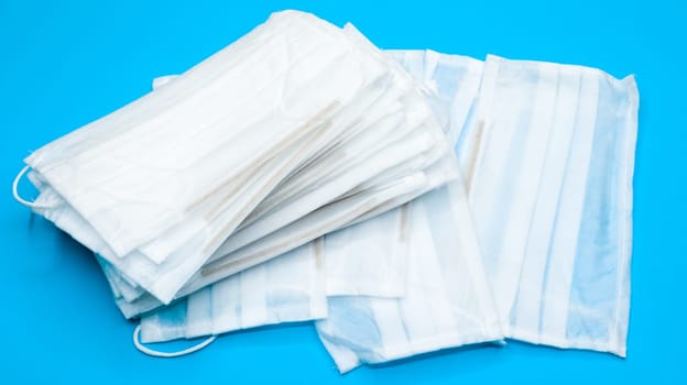 Coronavirus protection. Antiviral protective medical face masks with ear loops. Surgical mask background. Respiratory syndrome, coronavirus disease COVID-19. Many folded medical masks