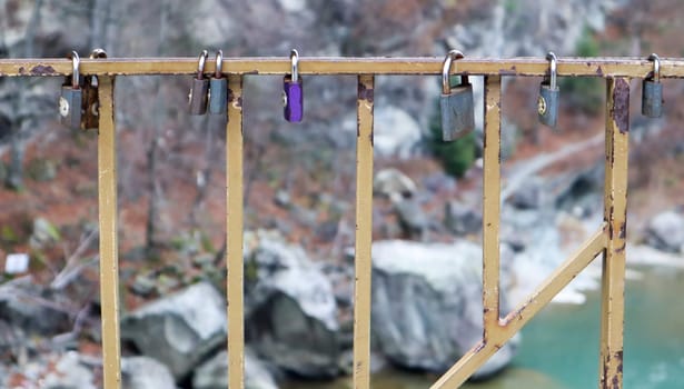 Many different locks hanging on the fence. The closed lock on the bridge - wedding tradition.