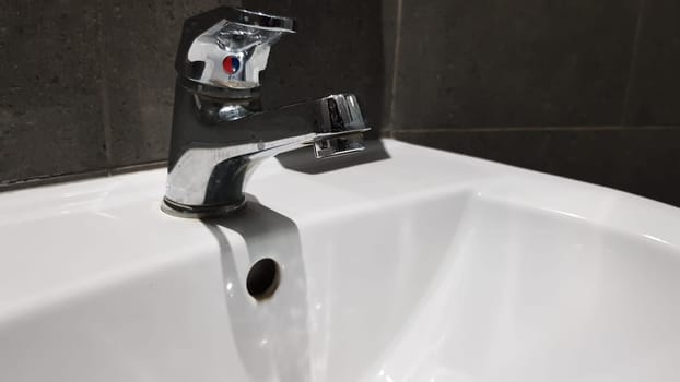 white ceramic washbasin with chrome faucet in the toilet with gray tile.