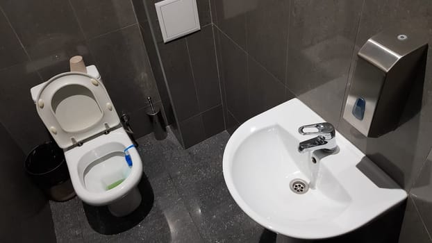 white ceramic washbasin with chrome faucet in the toilet with gray tile.