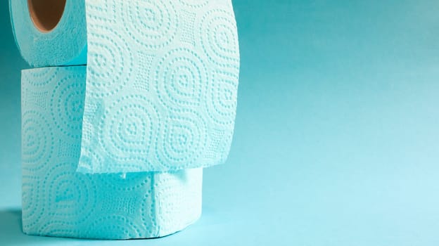 Blue roll of modern toilet paper on a blue background. A paper product on a cardboard sleeve, used for sanitary purposes from cellulose with cutouts for easy tearing. Embossed drawing. copy space