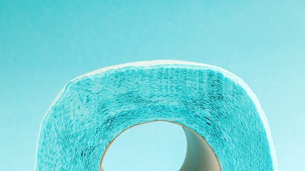 Blue roll of modern toilet paper on a blue background. A paper product on a cardboard sleeve, used for sanitary purposes from cellulose with cutouts for easy tearing. Embossed drawing. copy space