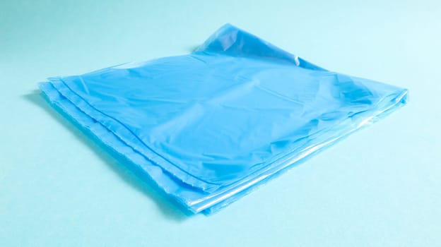 One torn plastic garbage bag in blue on a blue background. A bag that is designed to accommodate garbage in it and is used at home and placed in various garbage containers