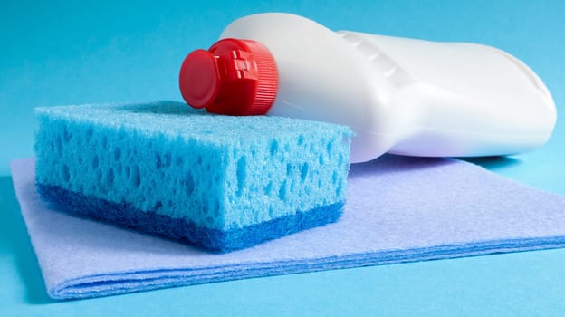 One blue sponge with a white bottle of detergent on a blue background. Convenience of sponges consists in good detergent retention that allows to use it economically.