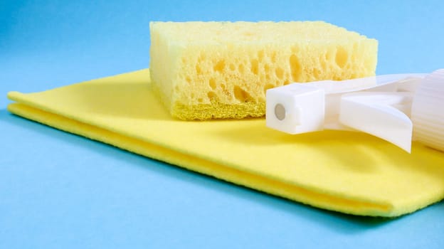 Set of cleaning products on a blue background. Yellow rag and sponge, cleaning spray, detergent. House cleaning concept