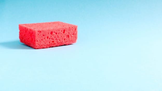 One red sponge on a blue background is used to wash and erase the dirt used by housewives in everyday life. They are made of porous material. Saving detergent, which allows you to use it sparingly.