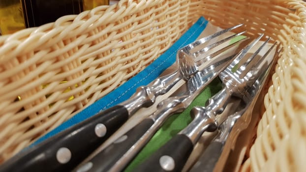 The served table in the restaurant. Fork, knife in a brown-yellow wicker pencil case