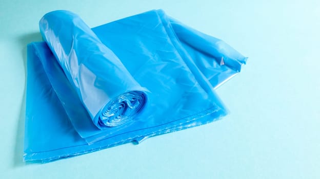 One roll of plastic garbage bags in blue on a blue background. Bags that are designed to accommodate garbage in them and used at home and placed in various garbage containers
