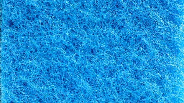 Background in the form of a porous structure in blue. Macro sponge. Close up blue sponge surface for textured background. copy space