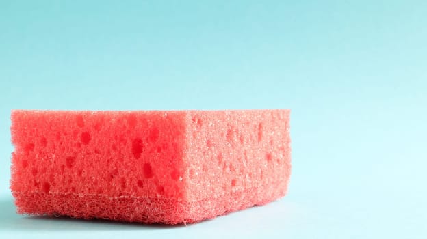 One red sponge on a blue background is used to wash and erase the dirt used by housewives in everyday life. They are made of porous material. Saving detergent, which allows you to use it sparingly.