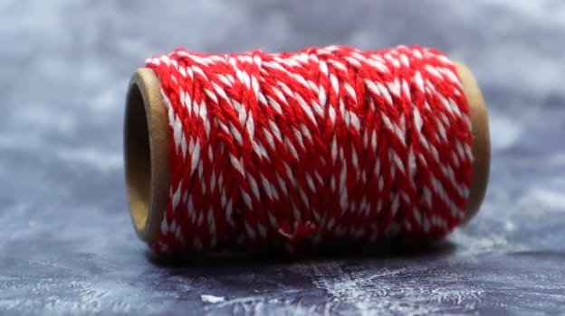 Baker's twine. Red and white lines. Red roll of woolen thread, close-up on gray marble background. Spool of decorative threads