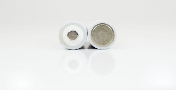 Two alkaline batteries on a white background with reflection. Energy supply and recycling concept. Copy space. Minimalism. Eliment AA is the most common type of galvanic batteries and accumulators